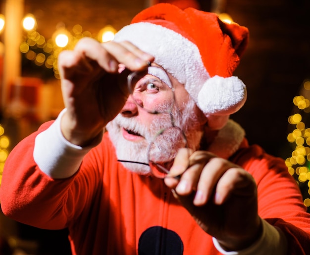 Hombre de santa con gafas rotas hombre barbudo en traje de santa mirando a través de anteojos rotos