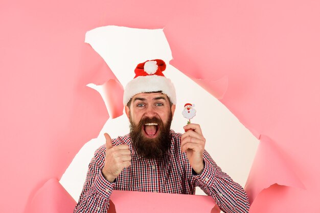 Hombre de santa mirando a través del agujero en el papel con poco santa rebajas de navidad descuento santa barbudo