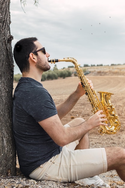 Hombre con saxofón mientras está al aire libre