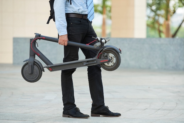 Hombre con scooter de pie al aire libre