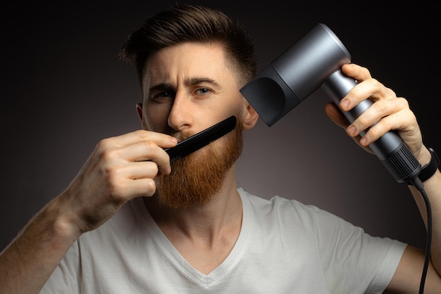 Un hombre se seca la barba con un secador de pelo