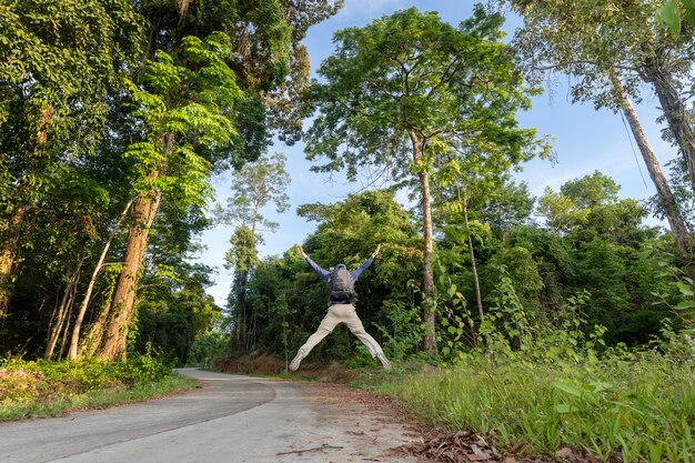 Hombre de senderismo y saltar sobre la carretera.