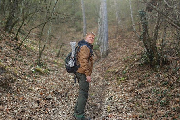 Un hombre se para en un sendero en el bosque con una mochila en la espalda.