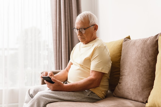 Hombre senior con anteojos está utilizando smartphone