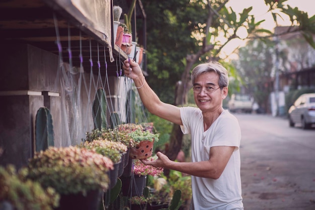 Hombre senior asiático sonriendo con cara de felicidad de pie en el jardín de casa