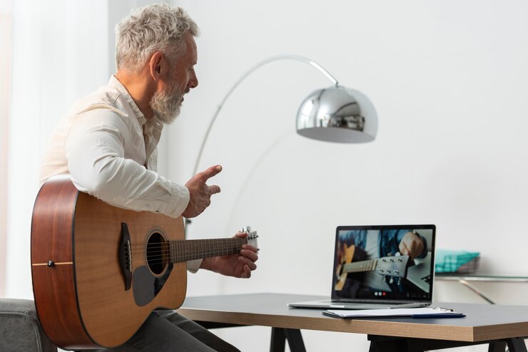 Foto hombre senior en casa estudiando lecciones de guitarra en portátil