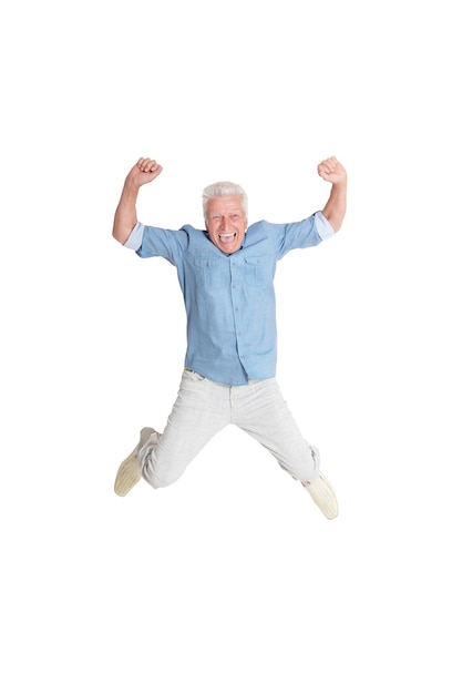 Hombre senior feliz en camisa saltando con las manos arriba sobre fondo blanco.