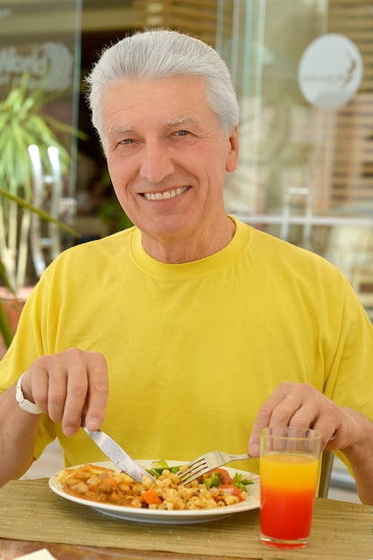 Foto hombre senior feliz desayunando en la cafetería