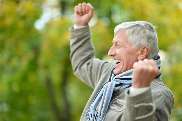 Hombre Senior feliz descansando en el parque en otoño