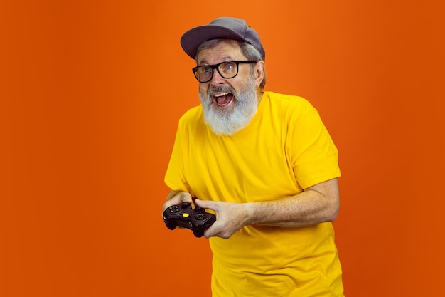 Hombre senior hipster usando dispositivos, gadgets sobre fondo naranja