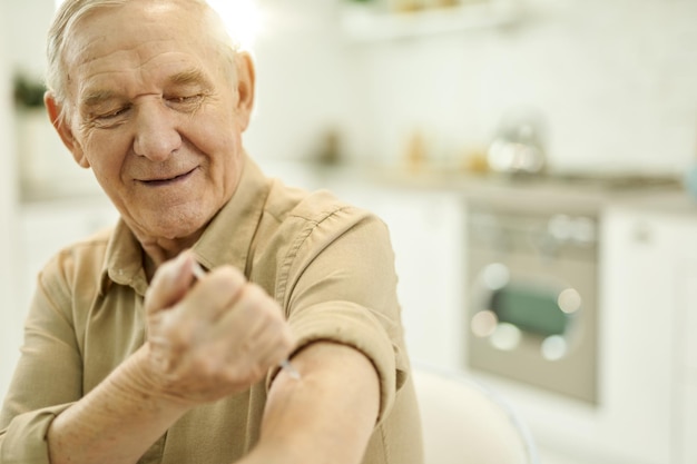 Hombre senior independiente dándose una inyección en el brazo