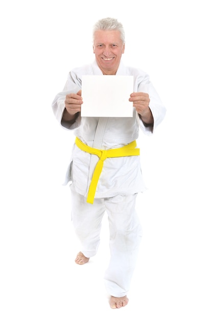 Hombre senior de karate con cartel blanco sobre fondo blanco.