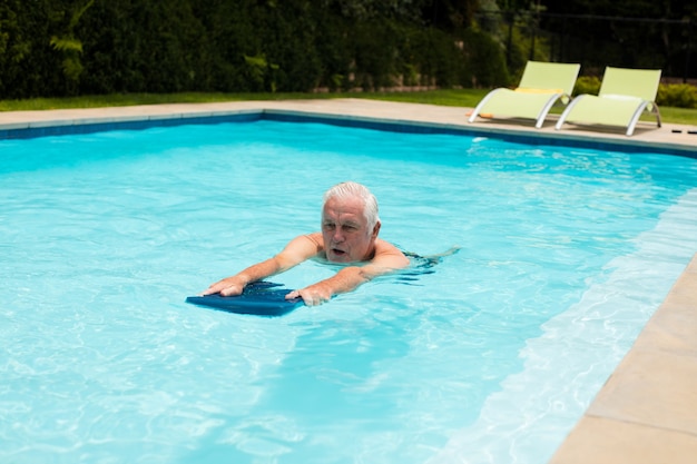 Hombre senior nadando en la piscina en un día soleado