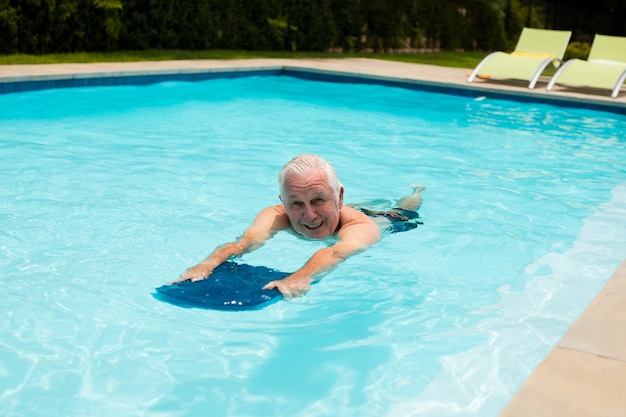 Hombre senior nadando en la piscina en un día soleado