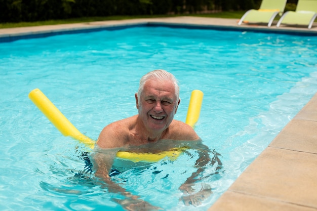 Hombre senior nadando con tubo inflable en la piscina