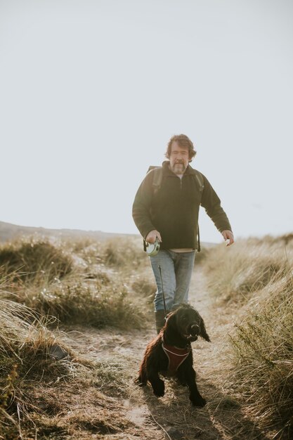 Hombre Senior paseando a su perro por un sendero costero