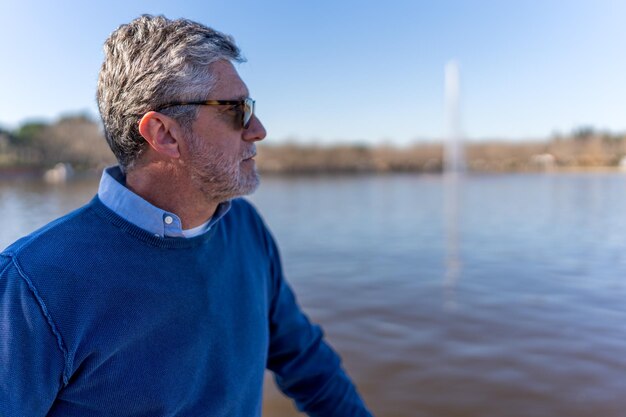 Hombre senior pensativo admirando el lago