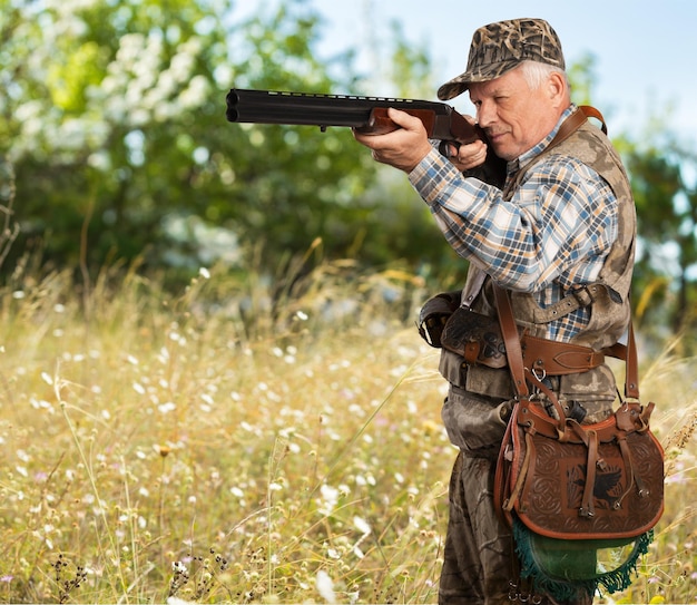 Hombre senior pensativo con pistola en el bosque