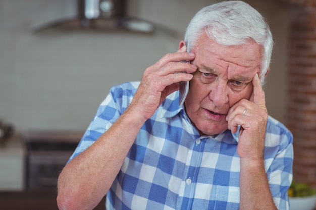 Hombre senior preocupado hablando por teléfono móvil