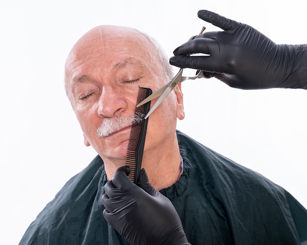 Hombre senior durante el proceso de aseo del bigote