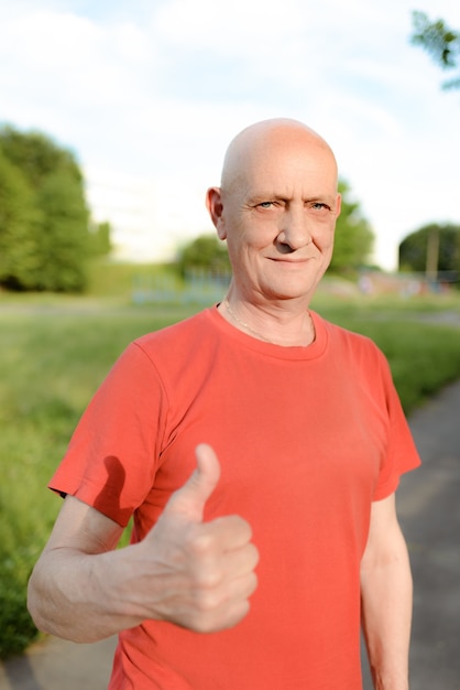 Hombre senior en ropa casual está sonriendo y mostrando el pulgar a la cámara