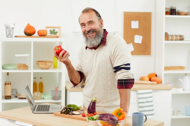 Hombre senior sonriente posando con pimiento