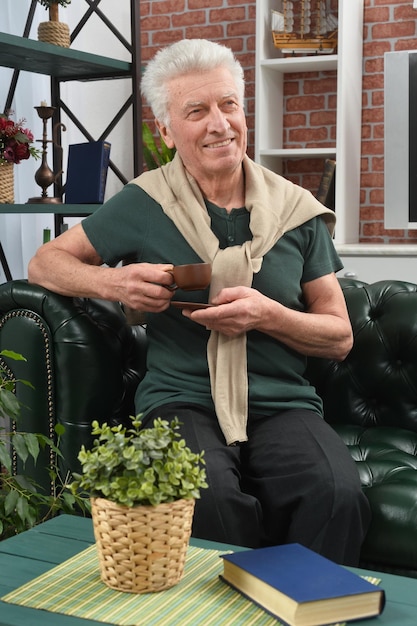 Hombre senior sonriente tomando café en casa