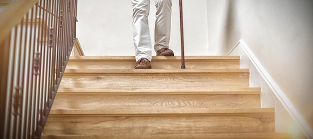 Hombre senior subiendo escaleras con bastón