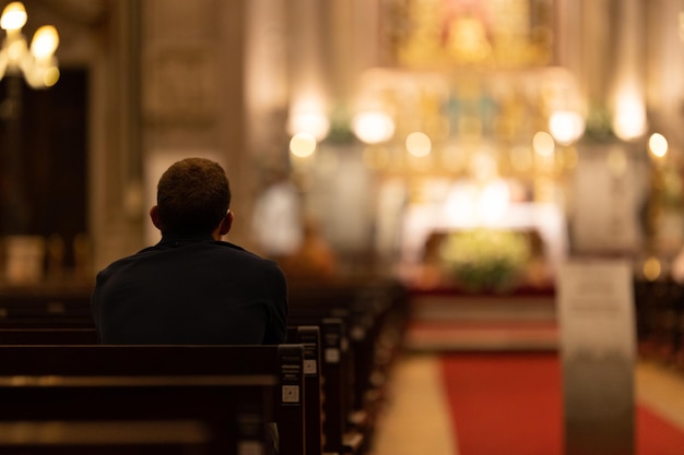 Un hombre sentado en un banco de la iglesia.