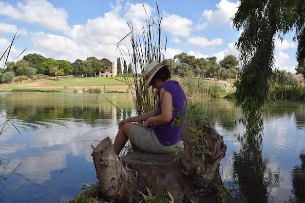 Foto hombre sentado en un banco junto al lago