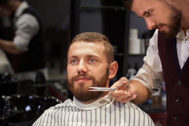 Hombre sentado en la barbería y corte de barba