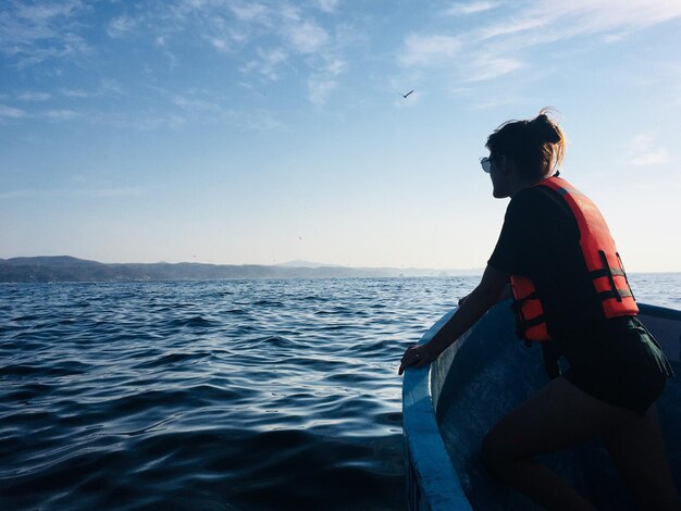 Foto hombre sentado en un barco en el mar contra el cielo