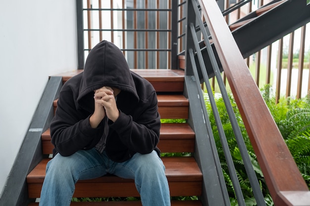 Un hombre sentado en una escalera y llorar. Hombre desempleado