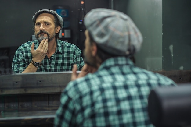 hombre sentado frente al espejo en la barbería