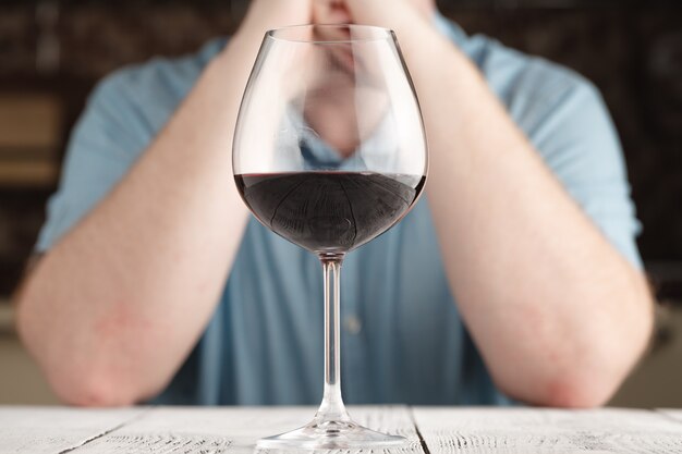 hombre sentado a la mesa con una copa de vino tinto