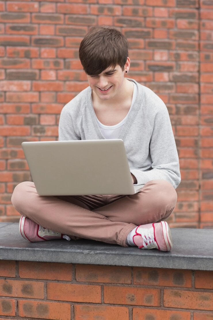 Foto hombre sentado con las piernas cruzadas y usando una computadora portátil fuera