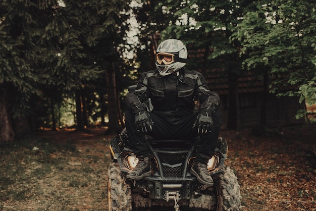 Hombre sentado en quad en el bosque y preparándose para montar