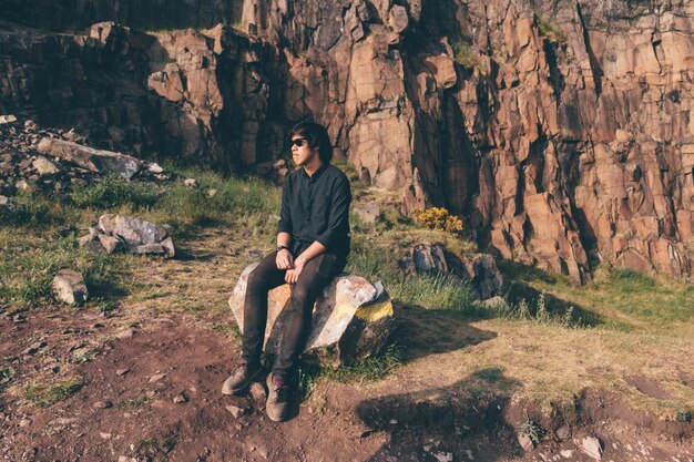 Foto hombre sentado en la roca contra la montaña