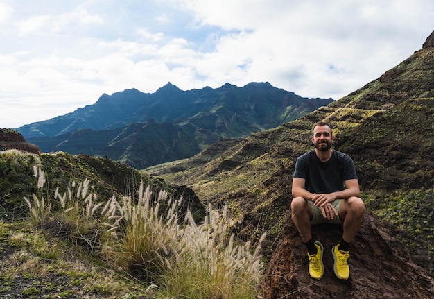 Hombre sentado en la roca rodeado de montañas en la naturaleza