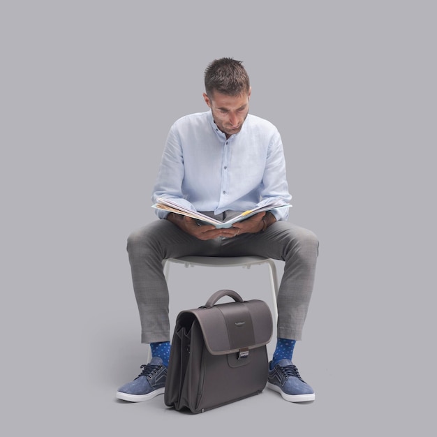 Hombre sentado en una silla y comprobando el papeleo está esperando una reunión