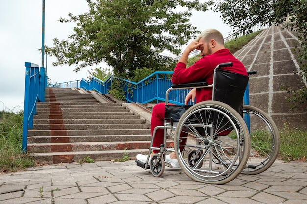 Un hombre sentado en una silla de ruedas se enfrenta solo a las dificultades, a la depresión. El concepto de silla de ruedas, persona discapacitada, vida plena, paralizada, persona discapacitada, atención médica.