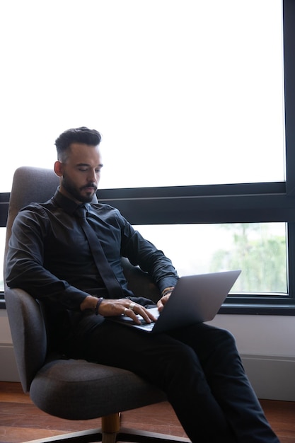 hombre sentado en un sillón trabajando en su computadora