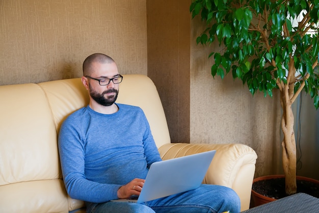 Hombre sentado en el sofá con laptop