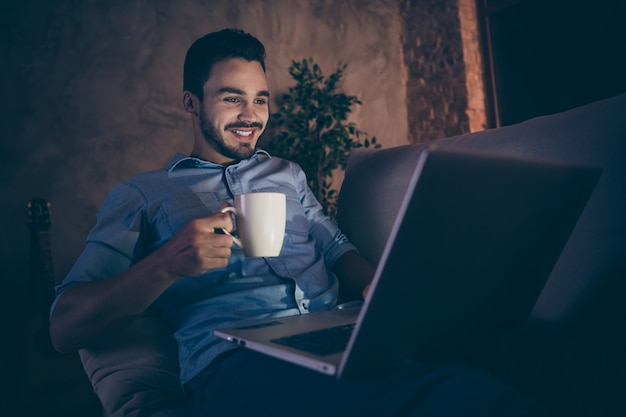 hombre sentado en el sofá y trabajando en la computadora portátil