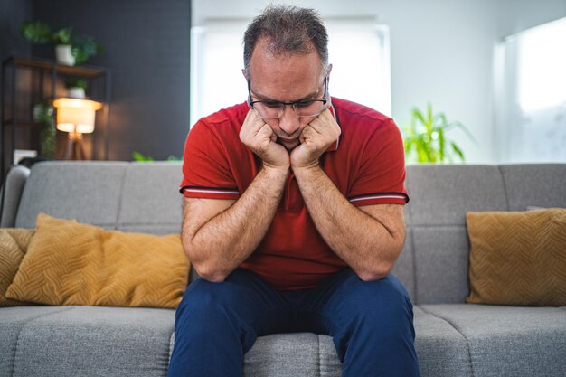 Hombre sentado solo en casa mirando triste y angustiado