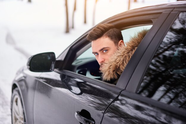 Hombre sentado en su coche en un bosque