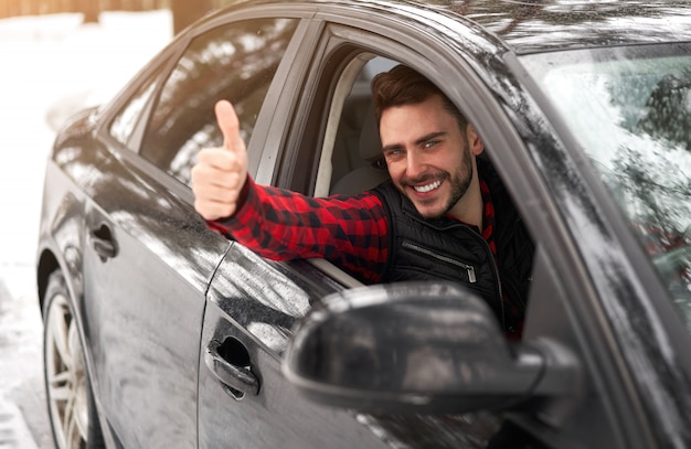 Hombre sentado en su coche en un bosque