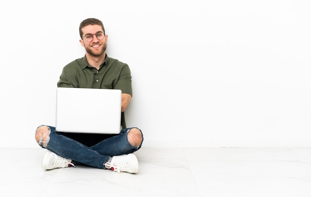 hombre sentado en el suelo con una computadora portátil