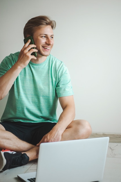 Hombre sentado en el suelo en comunicación con alguien aboman sentado pero trabajando en línea en la computadora ...