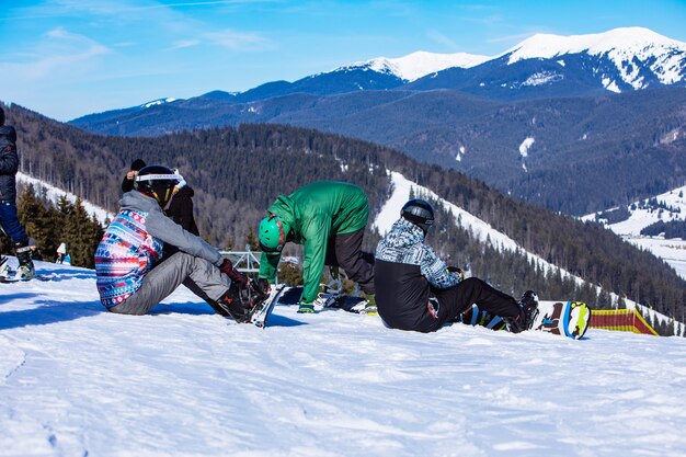 Hombre sentado con tabla de snowboard en la cima de la colina con hermosa vista. Copie el espacio. día soleado